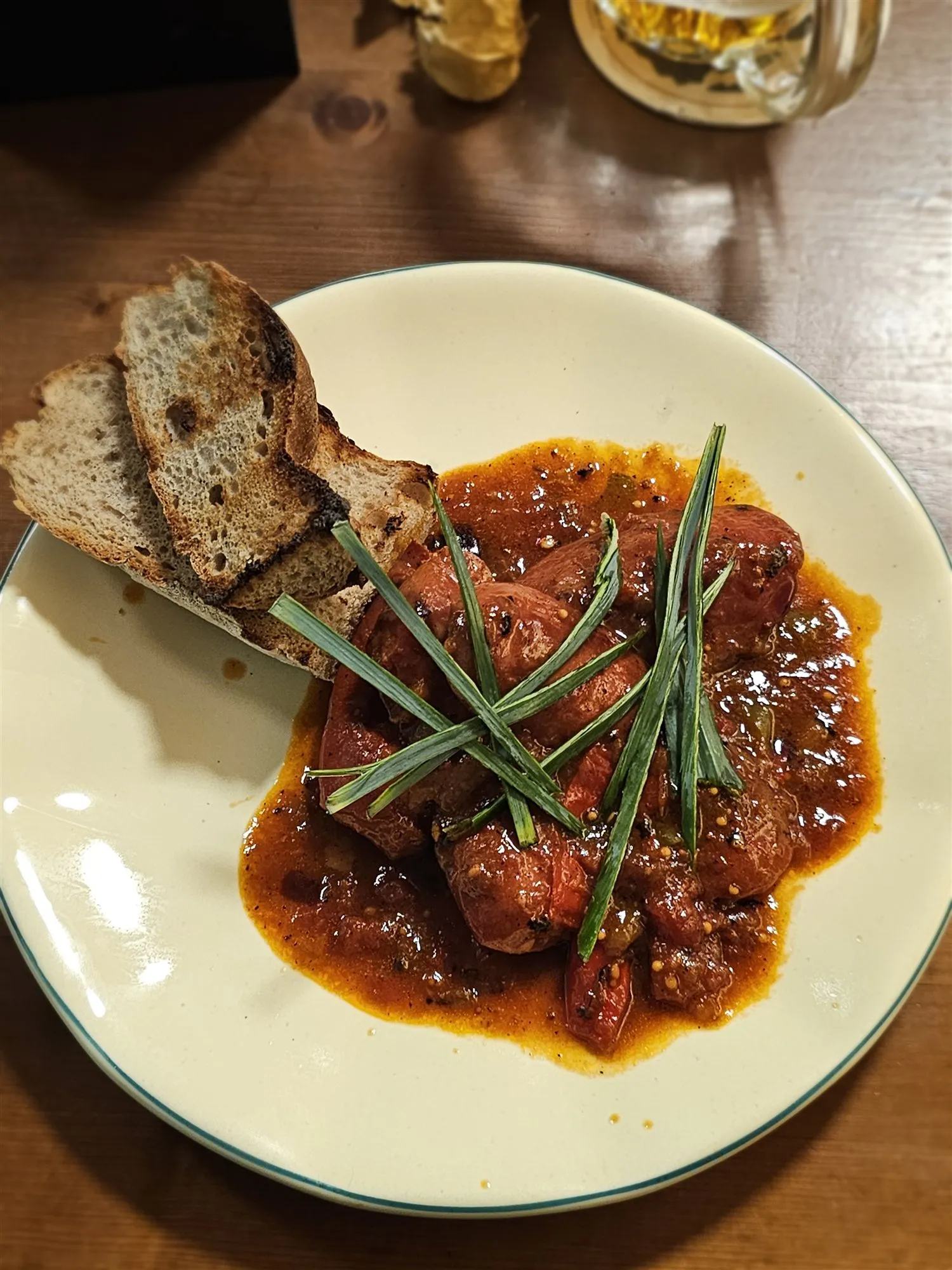 In Bier geschmorte Würste mit geröstetem Brot